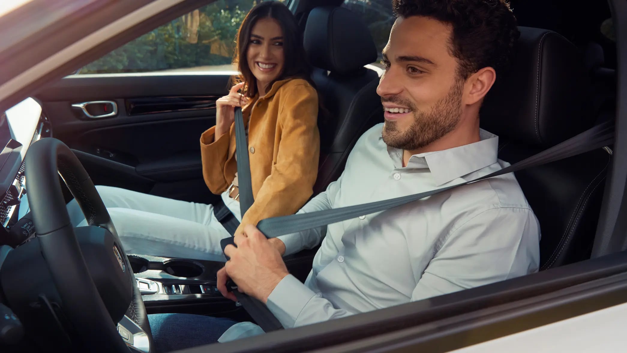 Dvaja ľudia si zapínajú bezpečnostné pásy vo vnútri vozidla Honda Civic Hybrid.